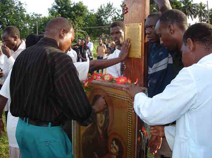 Fr. Paul Semkuya, before the Cross and Virgin Mary picture